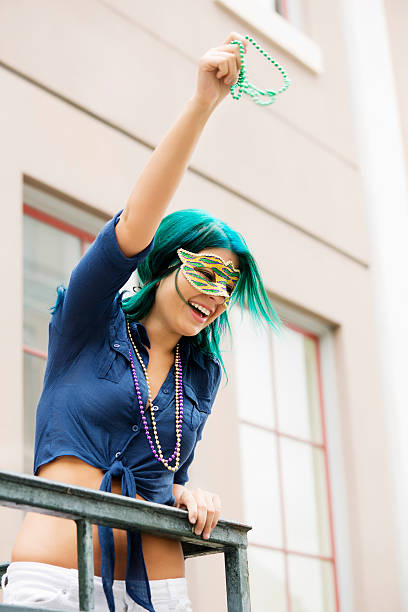 Young beautiful woman wearing mask in New Orleans "Young beautiful woman wearing a Mardi Gras mask outdoors in New Orleans, throwing beads. You might also be interested in these:" mardi gras women stock pictures, royalty-free photos & images