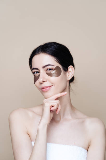 Young beautiful woman with clean fresh facial skin, uses eye patches Eye patch, Beautiful Woman With Natural skin And Green Hydro Gel Eye Patches under her eyes. Caucasian woman use patches after shower, skin care dark circles stock pictures, royalty-free photos & images