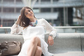 Young beautiful woman with white dress relaxing on bench