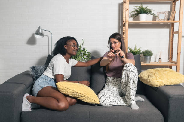 Young biracial lesbian homosexual couple sitting at home make a deal about quitting smoking cigarettes by one woman breaking the cigarette and her happy partner support her in that decision stock photo