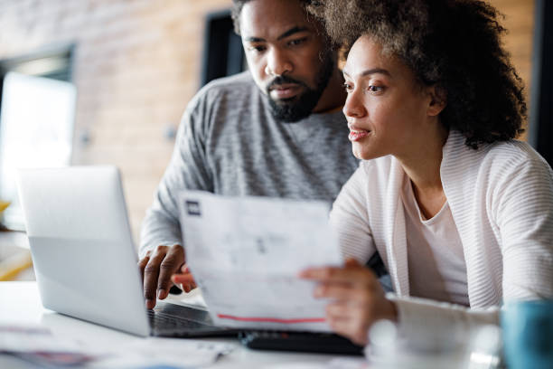 Young black couple paying their bills over laptop at home. stock photo