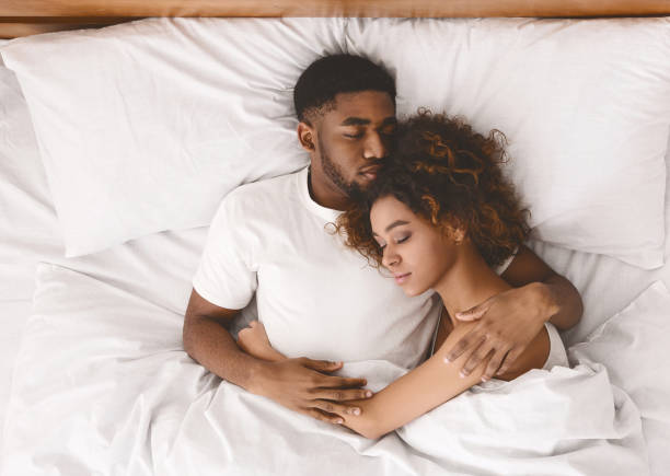 Young black couple sleeping together in bed Lovely black couple lying in white bed, sleeping together, top view man sleeping in bed top view stock pictures, royalty-free photos & images