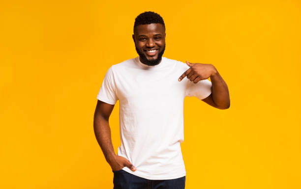 Young black man pointing at blank space of his clothes Look at my new t-shirt. Young black man pointing at blank space of his clothes one man only stock pictures, royalty-free photos & images