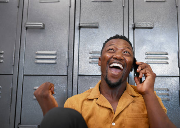 A young black student receives good news and looks excited on campus stock photo