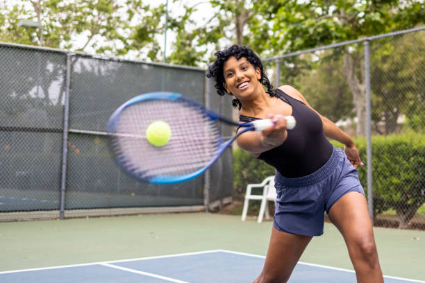 Young black woman hitting tennis ball stock photo