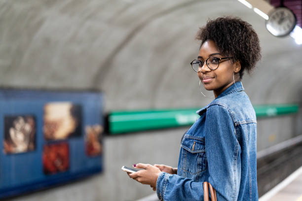 jonge zwarte vrouw met afro kapsel met behulp van mobiele in de metro - subway snapshot stockfoto's en -beelden