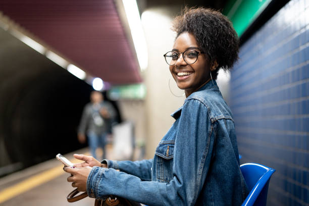 jonge zwarte vrouw met afro kapsel met behulp van mobiele in de metro - subway snapshot stockfoto's en -beelden