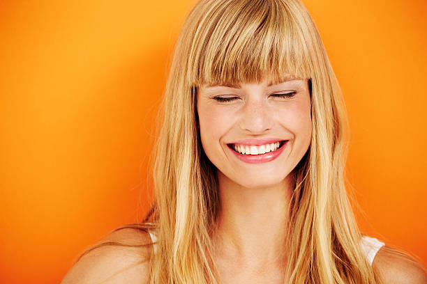 Young blond woman laughing Young blond woman laughing in studio blond hair stock pictures, royalty-free photos & images