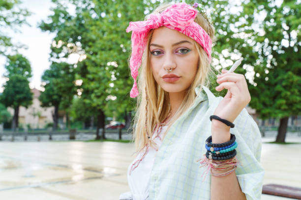 Young blonde caucasian woman standing outdoor with cigarette - Beautiful girl hold joint roll in summer day - Youth and freedom concept city life drugs cannabis legalization  little girl smoking cigarette stock pictures, royalty-free photos & images