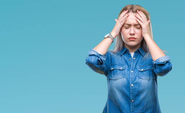 young blonde woman over isolated background suffering from headache desperate and stressed because pain and migraine. hands on head. - migraine imagens e fotografias de stock