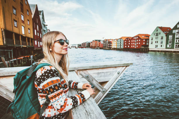 Young blonde woman traveling in Trondheim city Norway vacations weekend Lifestyle outdoor girl tourist with backpack sightseeing scandinavian architecture alone stock photo