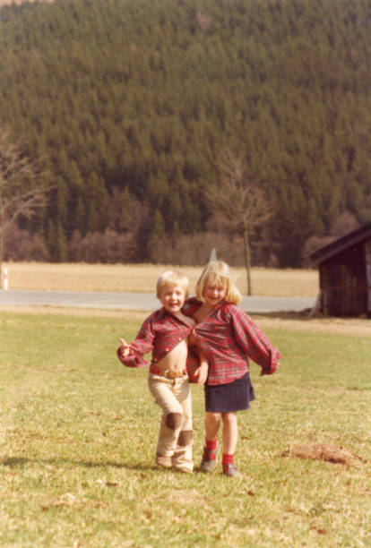1979 Young boy and girl having fun sharing and wearing an adult red squared shirt. 1979 Brother and sister having fun sharing and wearing an adult red squared shirt. blond hair photos stock pictures, royalty-free photos & images