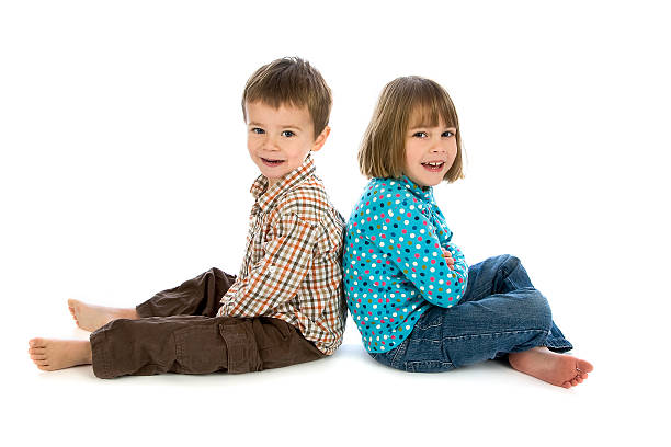 Young boy and girl sitting back to back on white stock photo