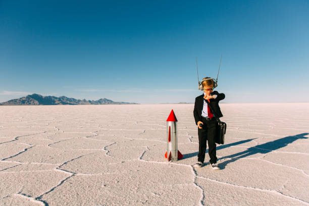 Young Boy Businessman Launching Rocket A young boy dressed in a business suit and tie stands on the Bonneville, Utah Salt Flats waiting for his new business and rocket to launch. He is wearing sunglasses and counting down to lift off while looking at his watch. The sky is blue and there is lots of copy space. countdown stock pictures, royalty-free photos & images