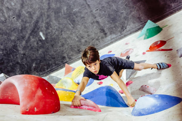 Young boy climbing an indoor climbing wall Young boy climbing an indoor climbing wall bouldering stock pictures, royalty-free photos & images