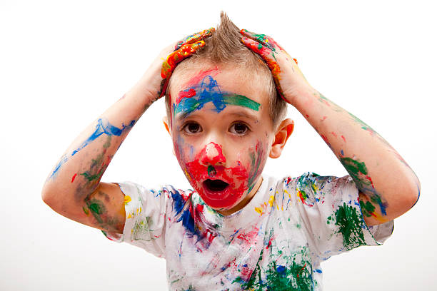 Young boy completely covered in many colors of paint stock photo