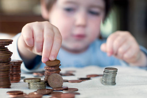A young boy counting his piggy bank money A three year old child stacks pennies. Narrow depth of field. UK allowance stock pictures, royalty-free photos & images