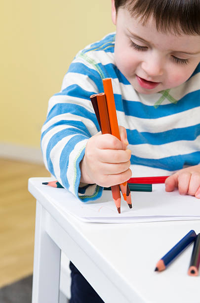 Young boy draws with three pencils stock photo
