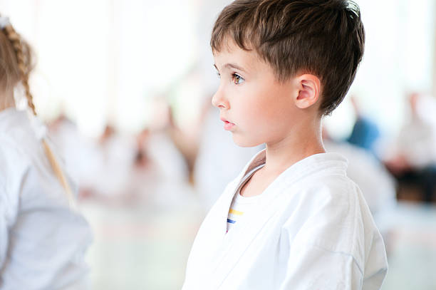 Young boy dressed in karate gear paying attention stock photo