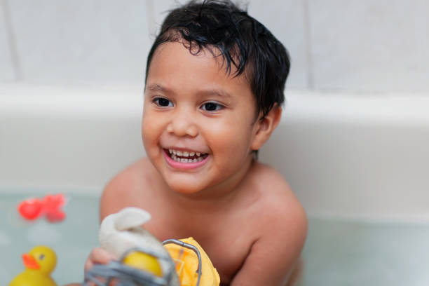 Young boy having fun and laughing during bath time and playing with toddler bath toys. stock photo
