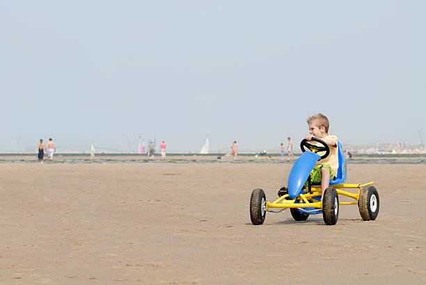 young boy in go-cart on the beach stock photo