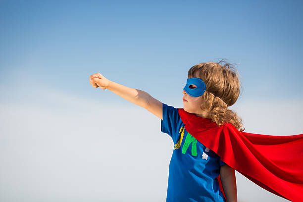 Young boy in red superhero cape and mask stock photo