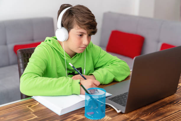 어린 소년이 노트북 앞에서 공부하고 있습니다. e 학습, 온라인 집에서 공부. - 멀리 떨어진 뉴스 사진 이미지