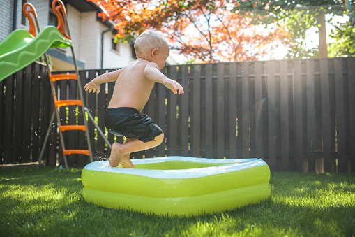 Young Boy Jumping Into The Inflatable Pool Stock Photo Download