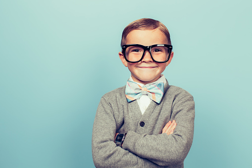 A young boy dressed as a nerd with glasses is looking in the camera...