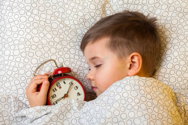 A young boy of 5 years deeply sleeps with a red watch stock photo