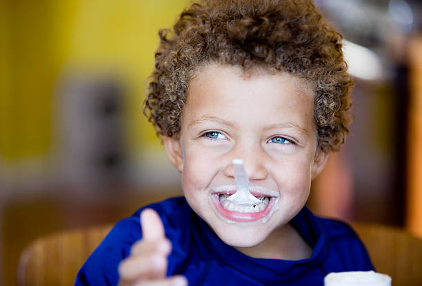 Young boy playing with this spoon while eating yogurt stock photo