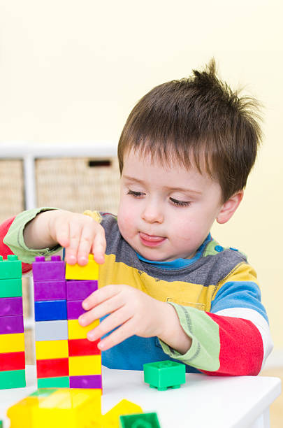 Young boy plays with connecting bricks stock photo