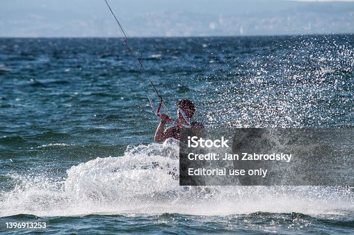 A young boy rides the sea on a kitesurfing in the waves on the island of Sardinia