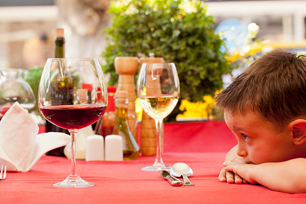 Young boy staring at a red and a white glass of wine stock photo
