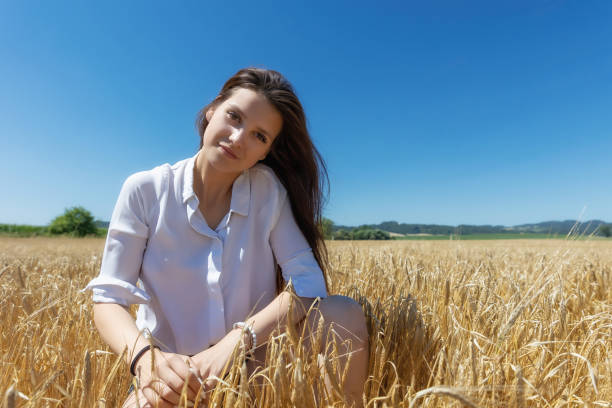 Young brunette is posing in a wheat field stock photo