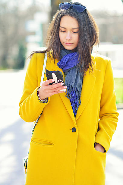 young brunette woman in a yellow coat, reads the message stock photo