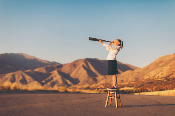 Young Business Girl Looks through Telescope A young business girl or student dressed in business attire stands on a stool looking through a telescope. She is searching for her next big opportunity to prove her success and abilities. She is confident looking in the mountains of Utah, USA. unemployment photos stock pictures, royalty-free photos & images