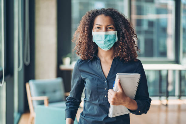 Young business woman with face mask in the office Businesswoman wearing a protective mask protective face mask photos stock pictures, royalty-free photos & images