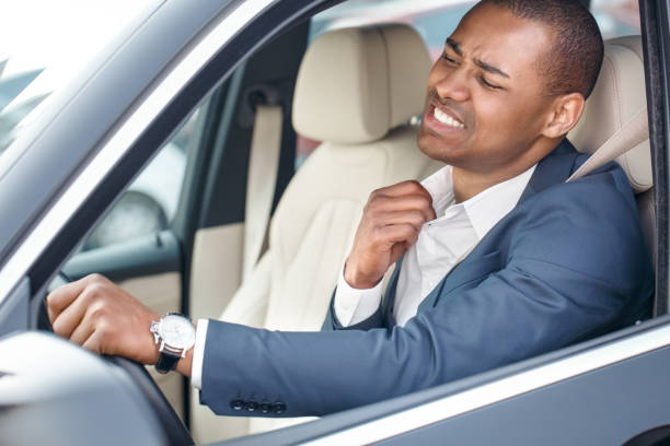Young businessman driver sitting inside car driving holding collar aside feeling hot side view in window close-up Young businessman driver sitting inside the car driving holding collar aside feeling hot uncomfortable side view in opened window close-up man driving suit stock pictures, royalty-free photos & images