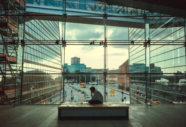 Young businessman sitting between glass buildings inside Black Diamond, modern part of Royal Danish Library stock photo