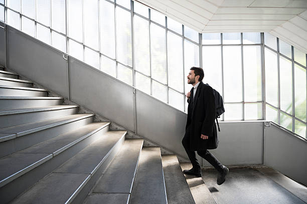 young businessman walking up stairs at railway station - stairs subway imagens e fotografias de stock