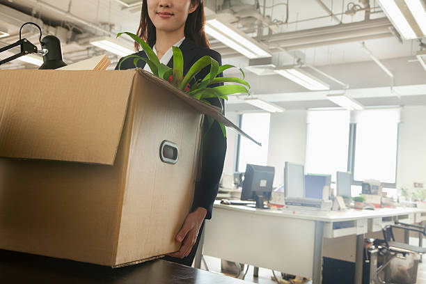 Young businesswoman carrying a box in an office stock photo