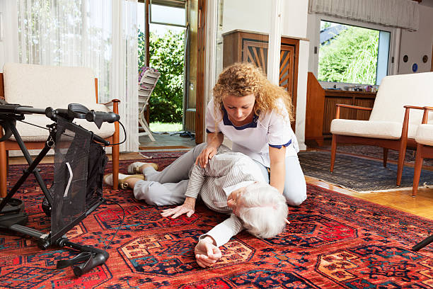 young caretaker helping senior woman lying after fall accident stock photo