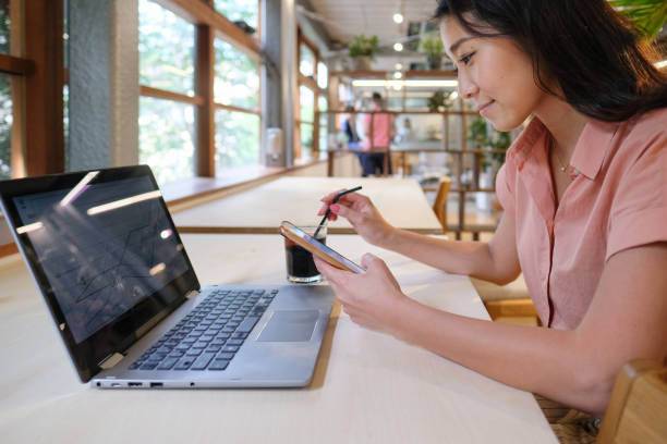 Young casual businesswoman working with PC and smart phone at cafe Asian remote working at cafe cafe culture stock pictures, royalty-free photos & images