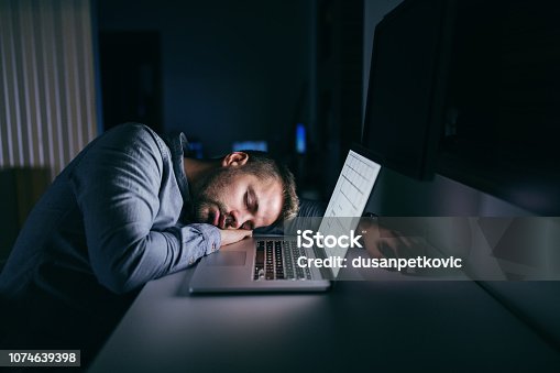 istock Young Caucasian businessman sleeping in the office late at night. Next to him laptop. 1074639398
