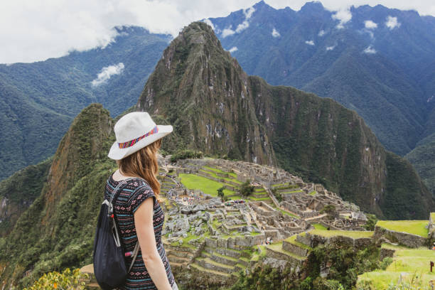 Young caucasian happy woman in Machu Picchu mountain and looking away in Peru. Back view with copy space Young caucasian happy woman standing in Machu Picchu mountain. Free solo female tourist in casual hat back view with copy space. Joyful adventure vocations in Peru beautiful peruvian women stock pictures, royalty-free photos & images