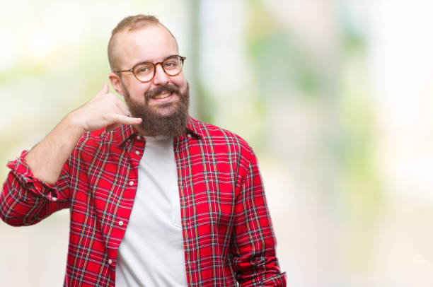 Young caucasian hipster man wearing glasses over isolated background smiling doing phone gesture with hand and fingers like talking on the telephone. Communicating concepts.  fat man looks at the phone stock pictures, royalty-free photos & images