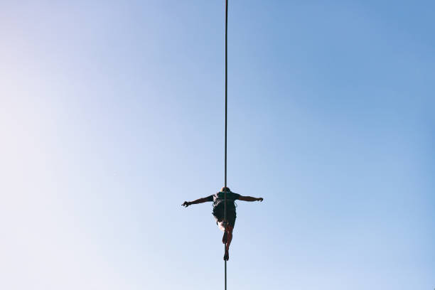 Young Caucasian slackline man practicing slackline against the sky on a clear summer day stock photo