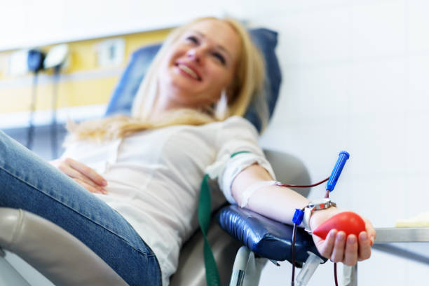 young caucasian woman with toy heart in the hand donates blood for saving lives and medical research young caucasian woman with toy heart in the hand donates blood for saving lives and medical research in some hospital at day time blood donation stock pictures, royalty-free photos & images