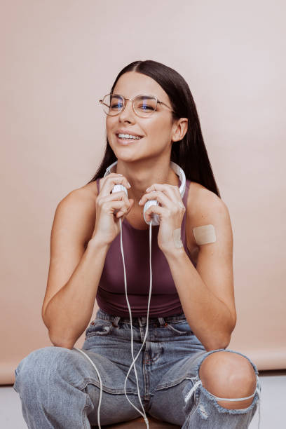 Young cheerful modern woman with headsets sits on stool at studio stock photo
